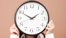 Woman holding a large clock in front of her face